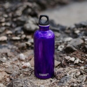 Close-up of a purple water bottle on rocky ground, perfect for outdoor adventures.